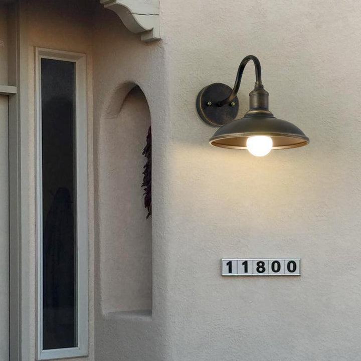Rund, lokkformet vegglampe med buet jernskjerm og enkeltflammedesign for terrassen