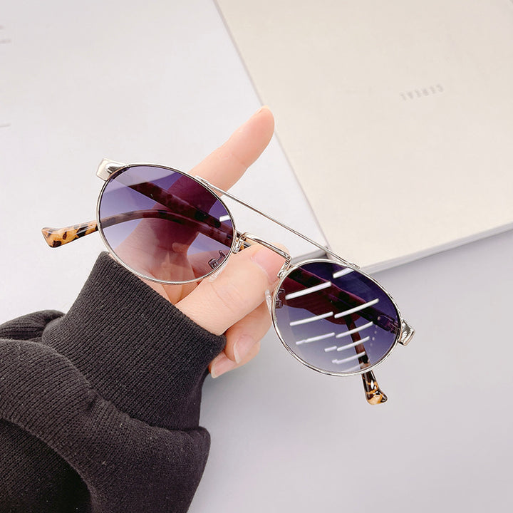 Dame moteriktig solbrille i stilfullt rundt design med gull aksenter Skanto