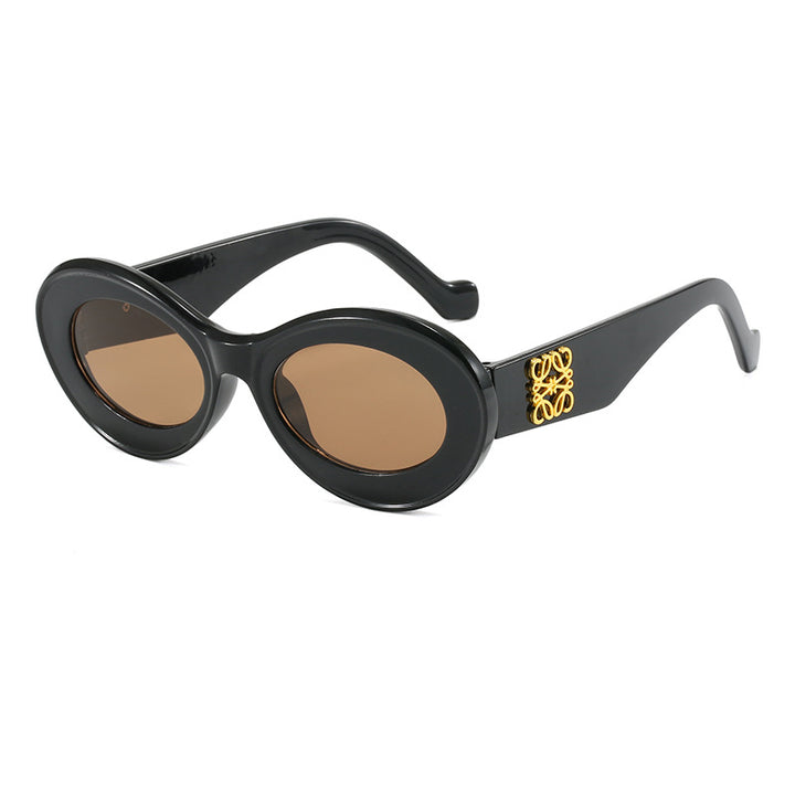 Dame moteriktig solbrille med oval ramme og gullapplikasjoner Skanto