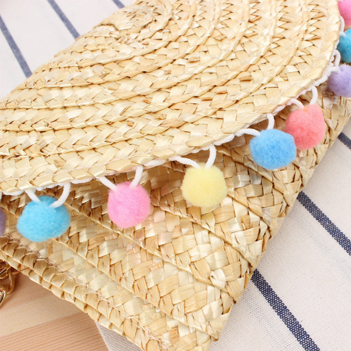 Hand-woven natural material clutch with decorative pom-poms Skanto