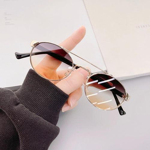 Dame moteriktig solbrille i stilfullt rundt design med gull aksenter Skanto